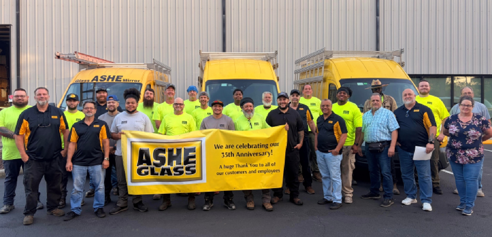 ASHE Glass team holding yellow anniversary banner