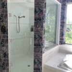 Glass shower and white tiled bathtub