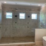 Glass-enclosed marble shower with dual rainheads