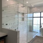 Glass-enclosed marble shower with water view
