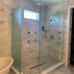 Glass-enclosed marble shower with rainfall showerhead
