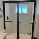 Black-framed glass shower in small bathroom