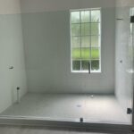 Empty white tiled shower with frosted window