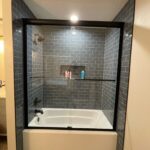 Glass-enclosed bathtub with gray subway tile