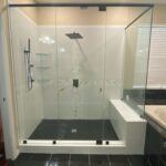 Modern glass shower with black tile floor