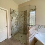 Glass shower with marble tile and tub