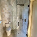 Small tiled bathroom with glass shower and toilet