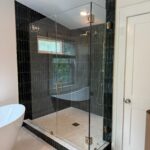 Glass corner shower with black vertical tiles