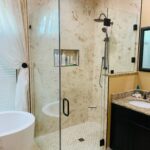 Glass shower enclosure with marble tile walls