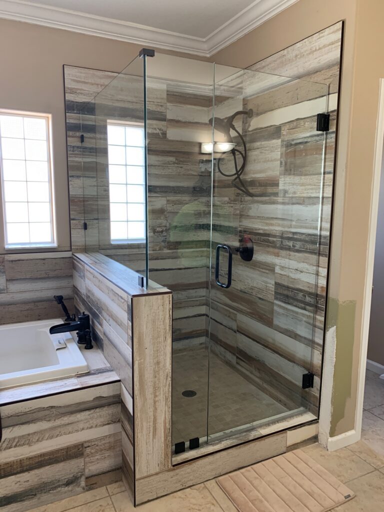 Glass shower enclosure beside bathtub in bathroom