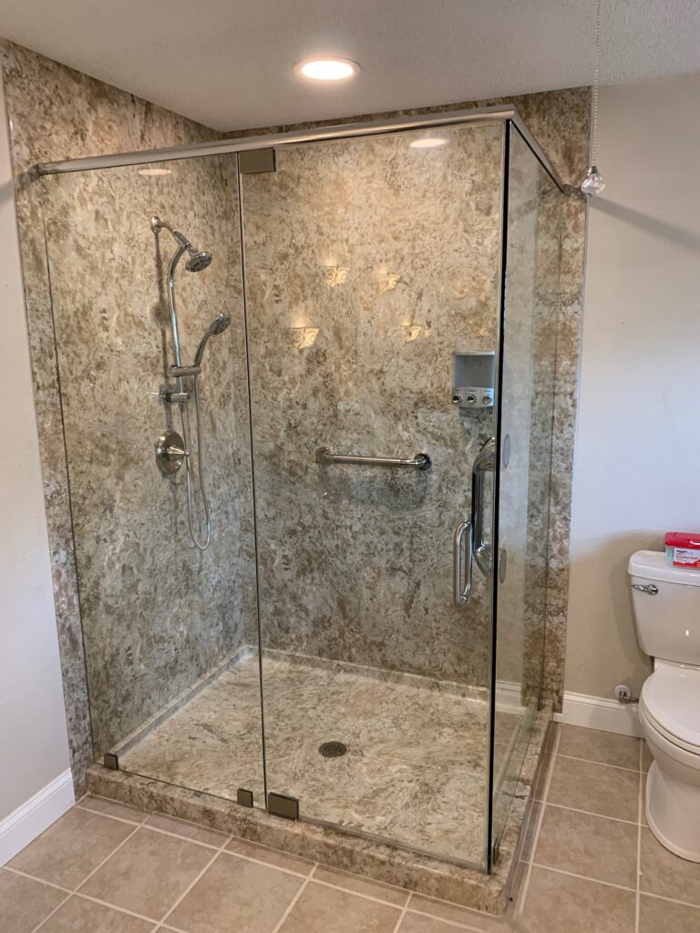 Glass-enclosed marble shower with chrome fixtures