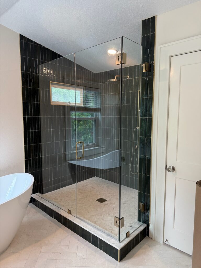 Glass-enclosed shower with dark vertical tiles